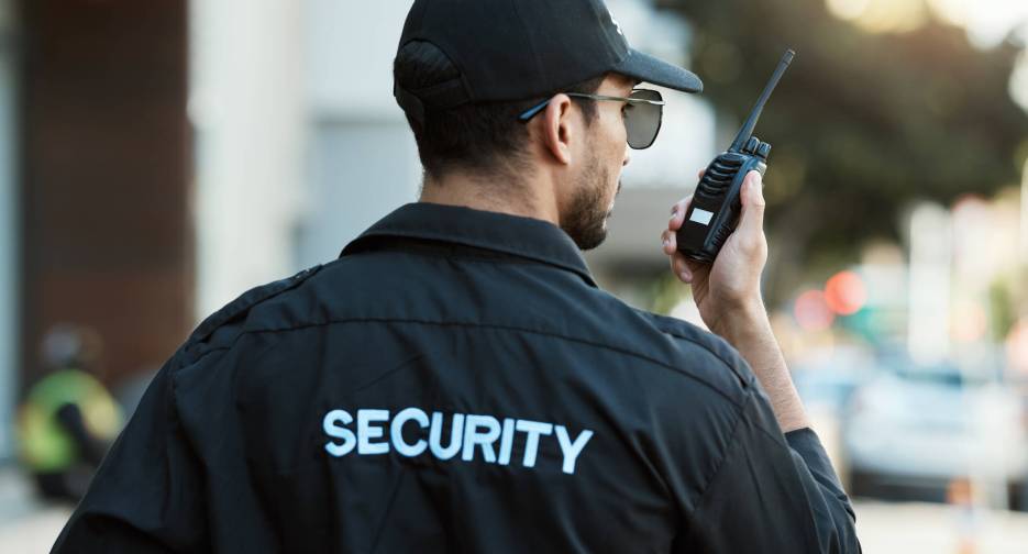 Radio, man and a security guard or safety officer outdoor on a city road for communication. Back of.